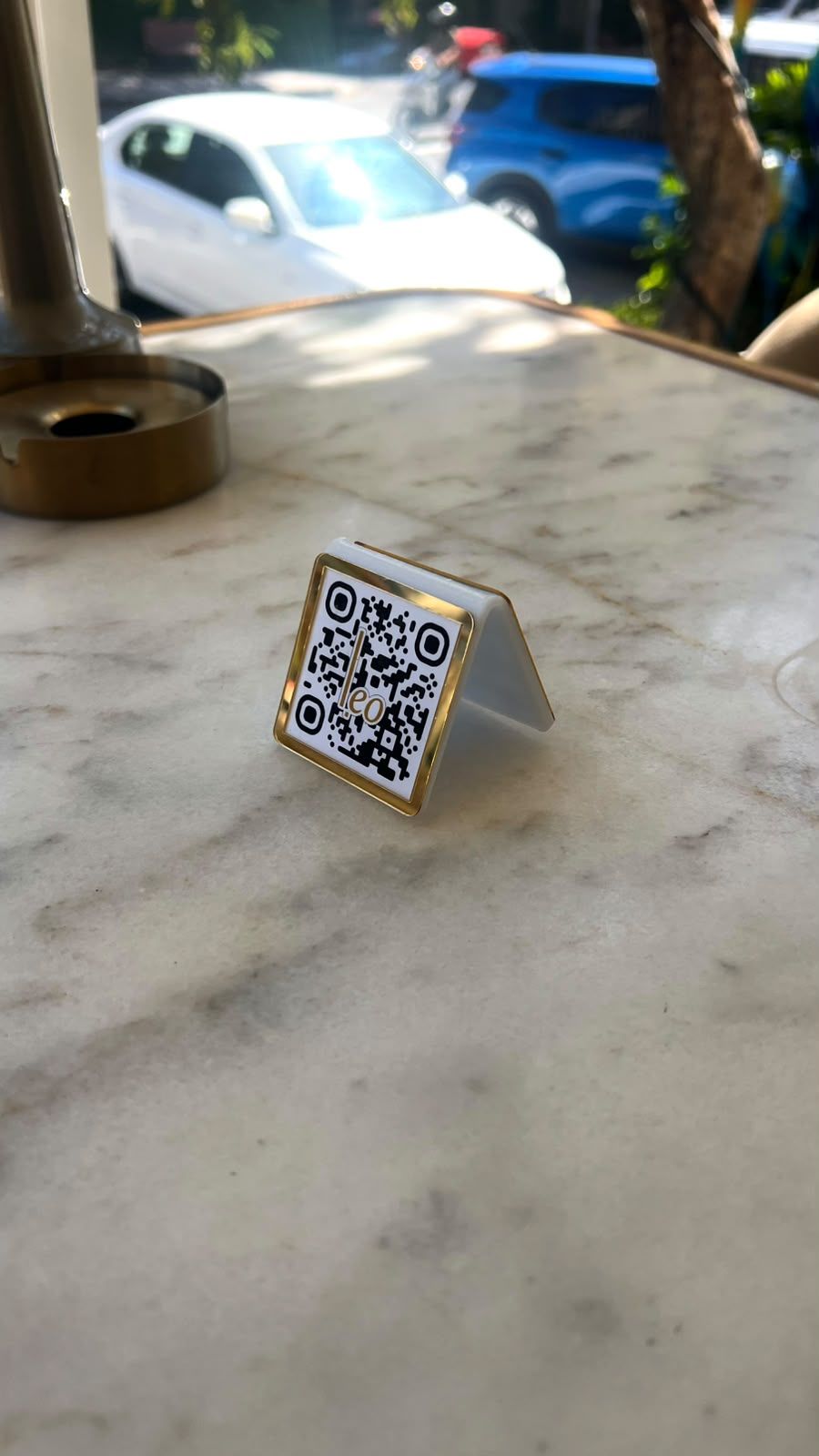 Mermer masa üzerinde altın çerçeveli, Leo logolu QR menü standı